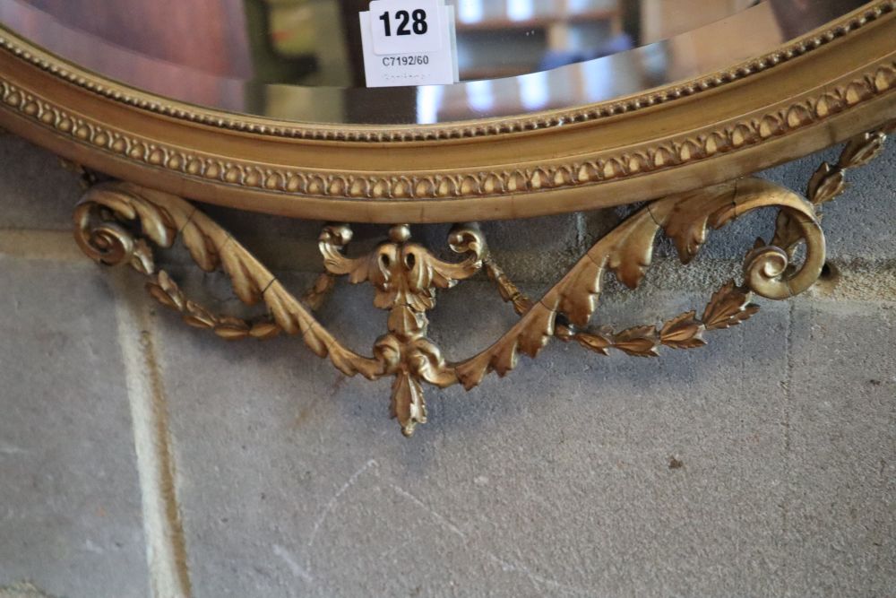 A late Victorian gilt oval wall mirror, surmounted by an urn, flanked by winged griffins, width 70cm height 75cm